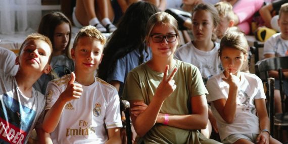 Cheerful group of children sitting together at an indoor event, showcasing friendships and diversity.